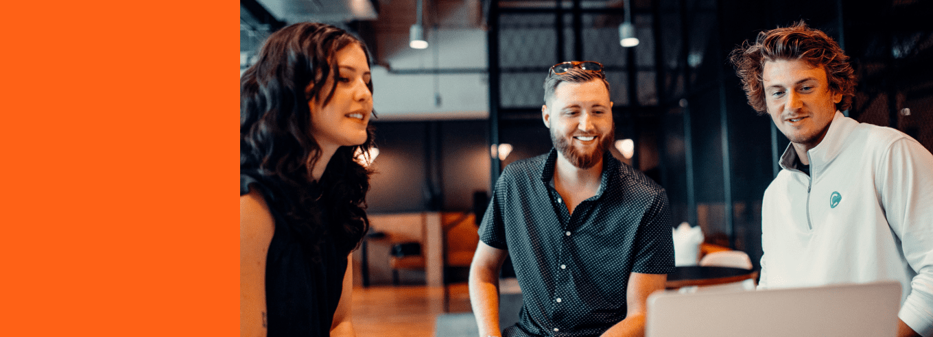 Three colleagues smiling around a laptop in a bright office, representing Material's customer experience consulting.